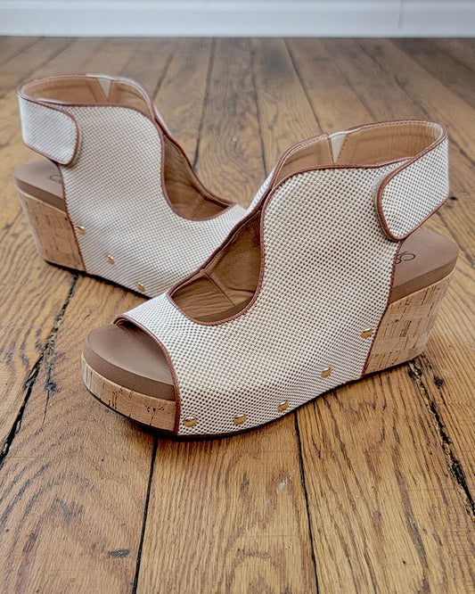 The Frisky Sandal from Corkys features beige mesh uppers, cork heels, and gold stud accents for a stylish look and comfort—shown here on a wooden floor.