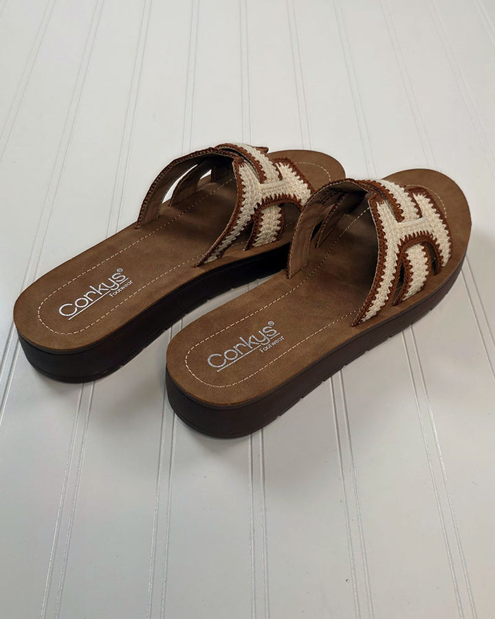 The On the Edge Sandal from Corkys features brown and beige crochet H-straps, thick soles, and woven details—perfect boutique sandals for summer, shown on a white textured surface.