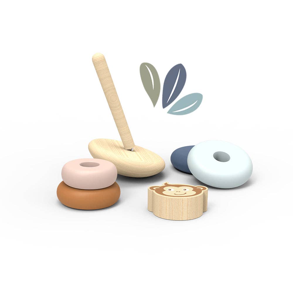 The Roly Poly Stacker by Speedy Monkey is a delightful wooden stacker crafted from FSC Certified Wood, featuring a peg, three vibrant rings, and a block with a monkey’s face. Each piece is thoughtfully arranged on a white surface decorated with leaf-shaped graphics in the background.