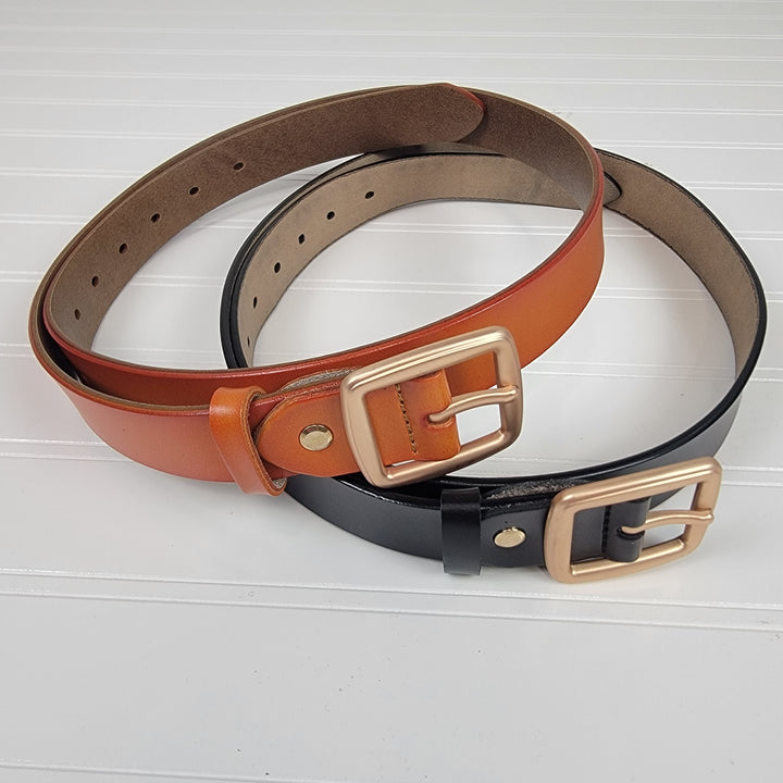 Two Leto Collection Brass Buckle Belts, one brown and one black, are shown overlapping on a white ridged surface.
