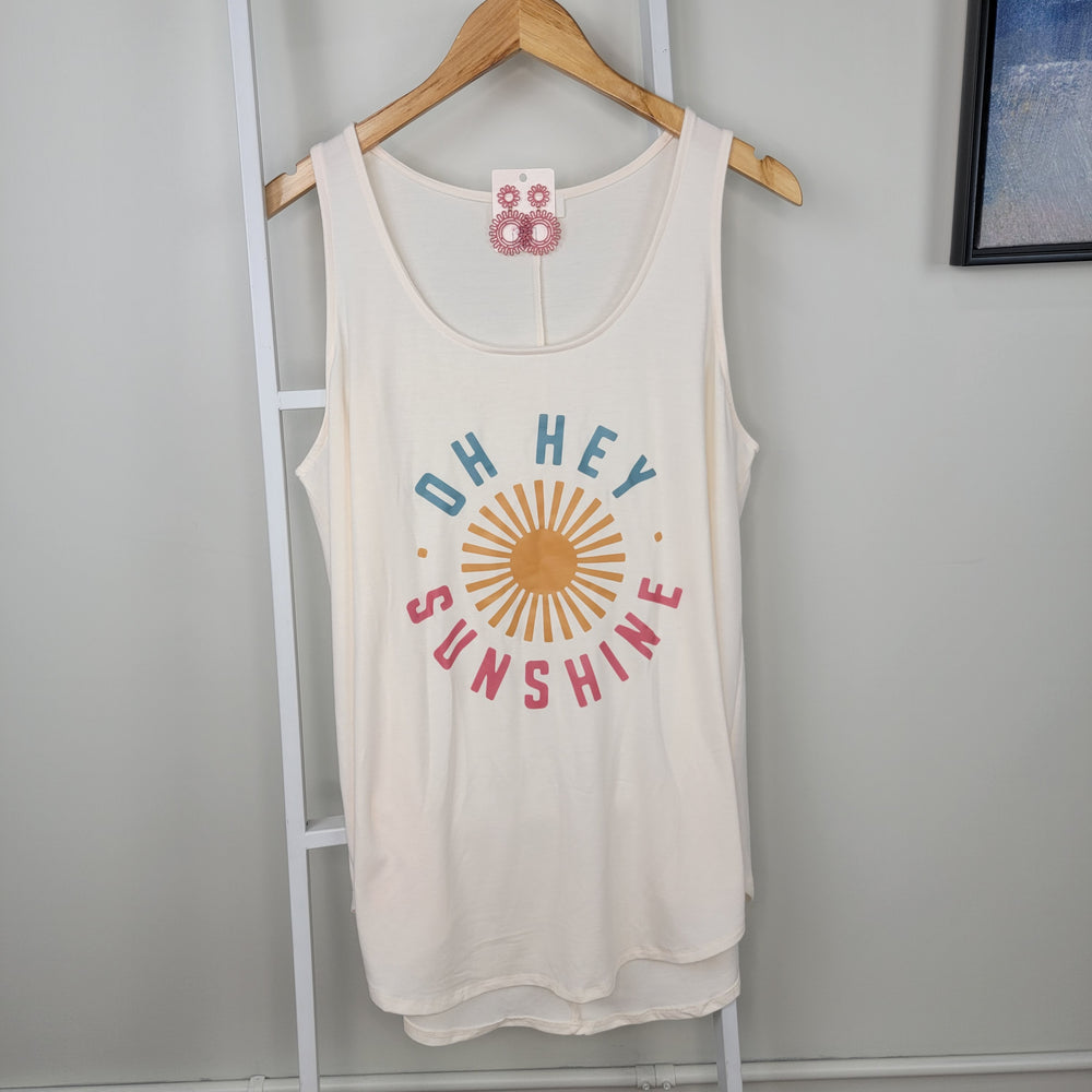 The Zenana "Oh Hey Sunshine" Tank is a lightweight, sleeveless white top with colorful text and a yellow sun graphic, displayed on a wooden hanger.