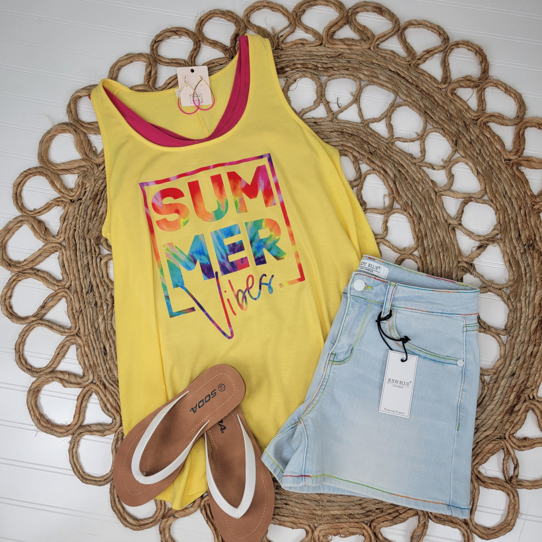 Flat lay of the Zenana Summer Vibes Tank, light-wash denim shorts with tag, and brown sandals on a woven mat over a white wooden background.