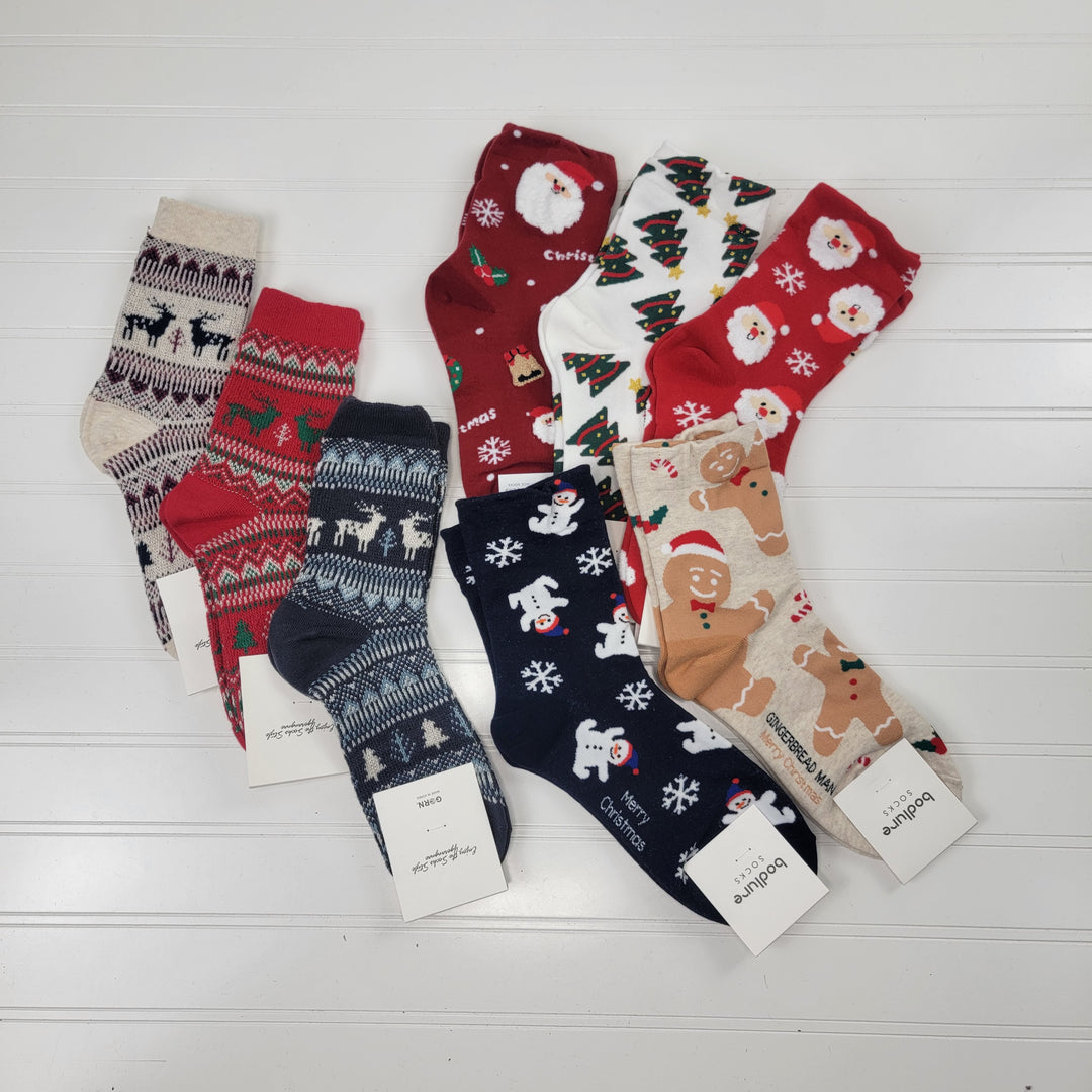Nine pairs of Gracelet Collection’s Socks - Christmas, featuring festive designs like reindeer, snowflakes, Santa faces, polar bears, trees & gingerbread men, are laid out on a white surface. These one-size socks add cheer to any holiday celebration.