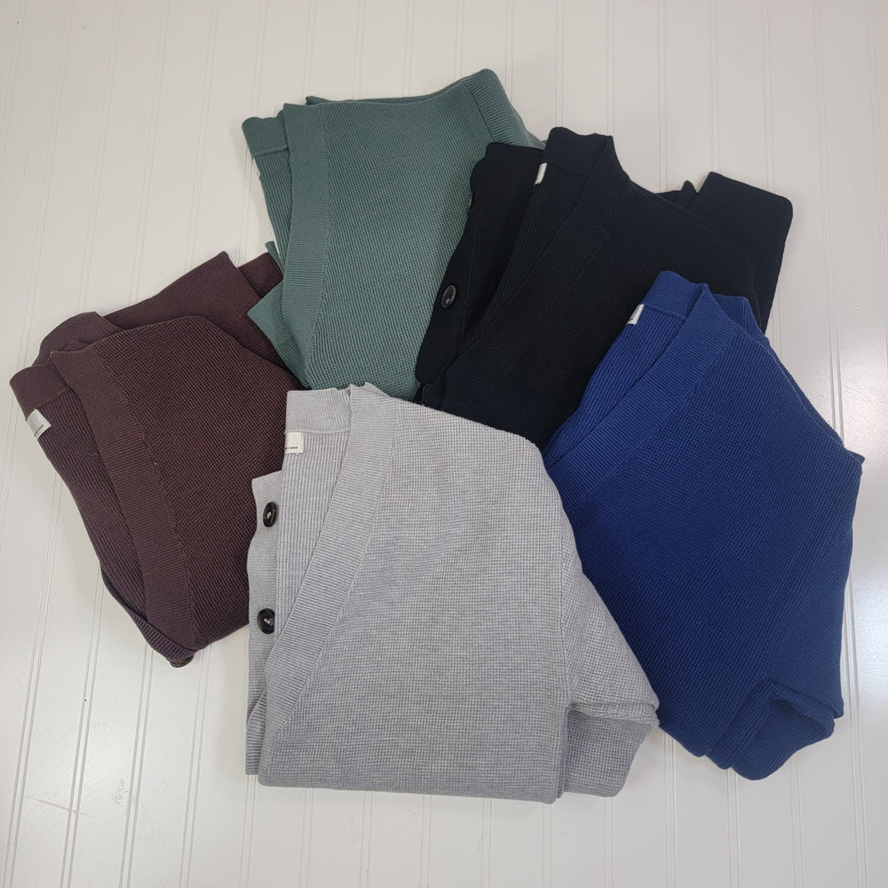 Five Nola Cardigans by Zenana—featuring drop shoulder and stretchy knit styles in burgundy, green, black, gray, and blue—are folded in a circle on a textured white surface.