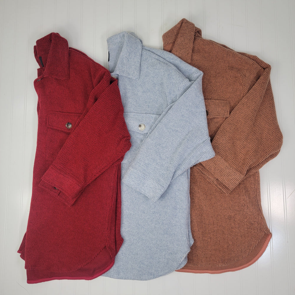 Three Timing "Gracie Shacket" corduroy button-front shackets in red, light blue, and brown are displayed side by side. Each medium-weight shacket features long sleeves and a buttoned front chest pocket.