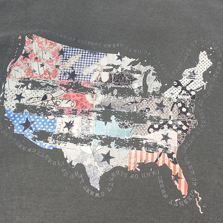 The Distressed USA Tee by Cosmos + Clover Boutique features a USA map with stripes, stars, florals, and checks on a gray 100% cotton Comfort Colors shirt. Surrounding text fades around the design for a unique look.