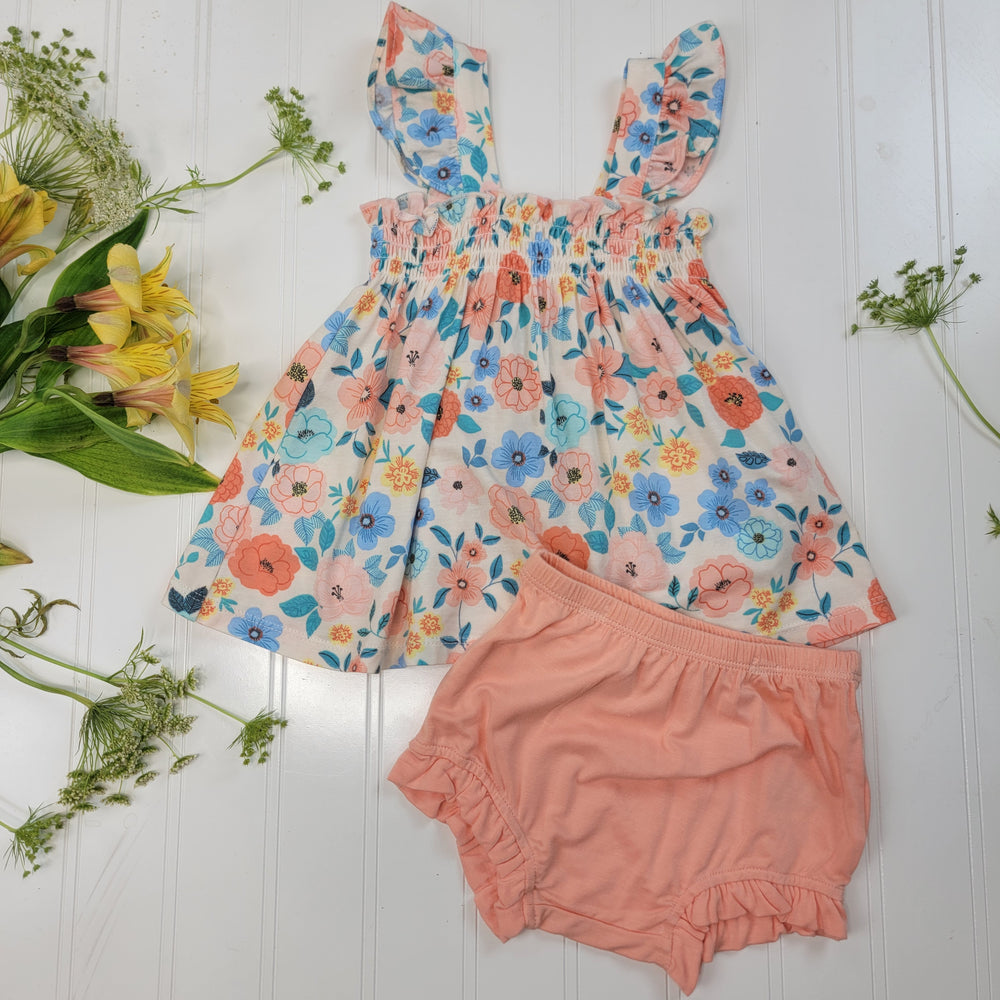 The Angel Dear Summer Baby Clothes set features a floral sleeveless dress with ruffled straps and matching peach shorts, displayed on a white surface with yellow and green flowers—perfect for toddler girls this summer.