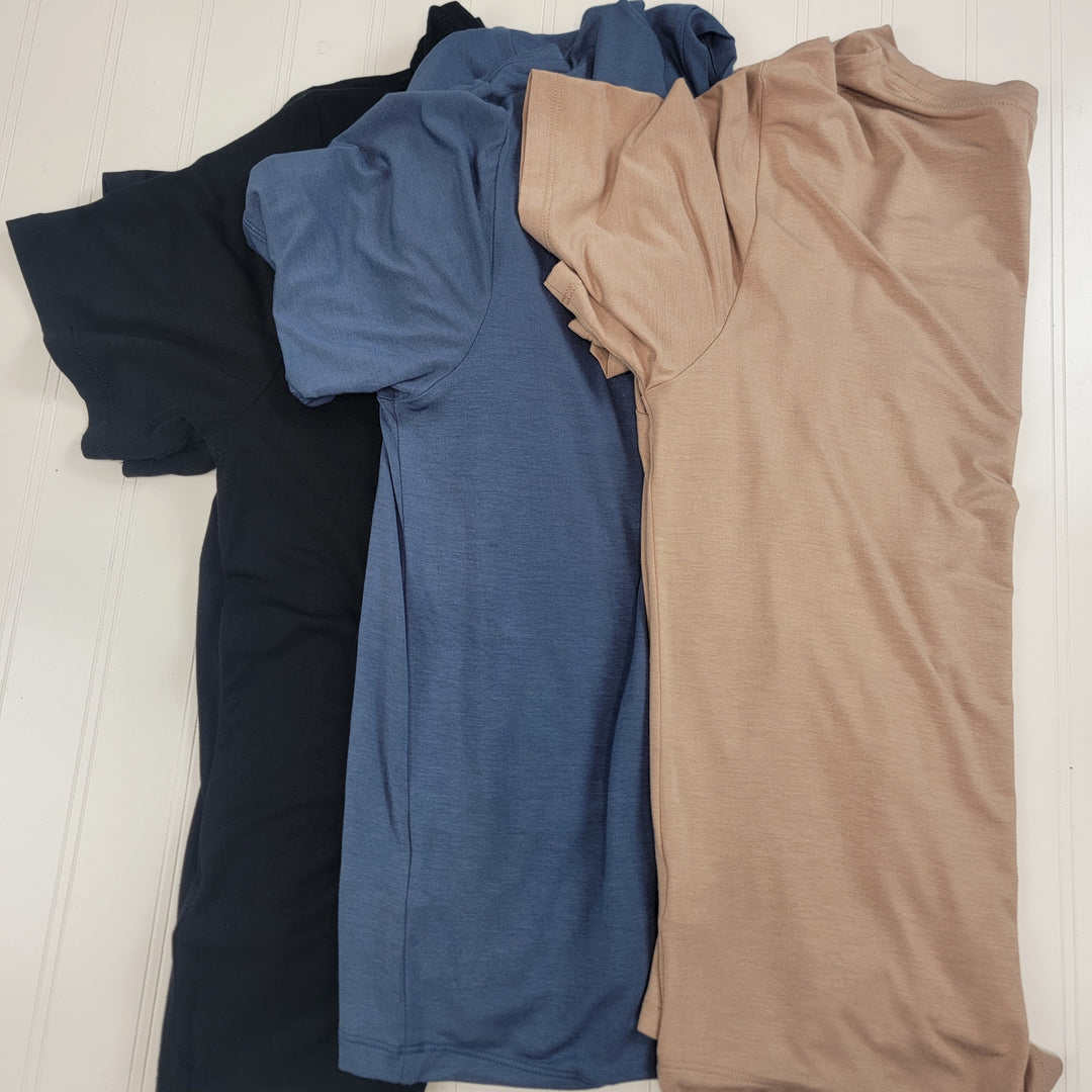 Three HYFVE, Inc Khloe Tees—short-sleeved crew necks in black, blue, and beige—are laid flat side by side on a white wooden surface with slightly overlapping sleeves.