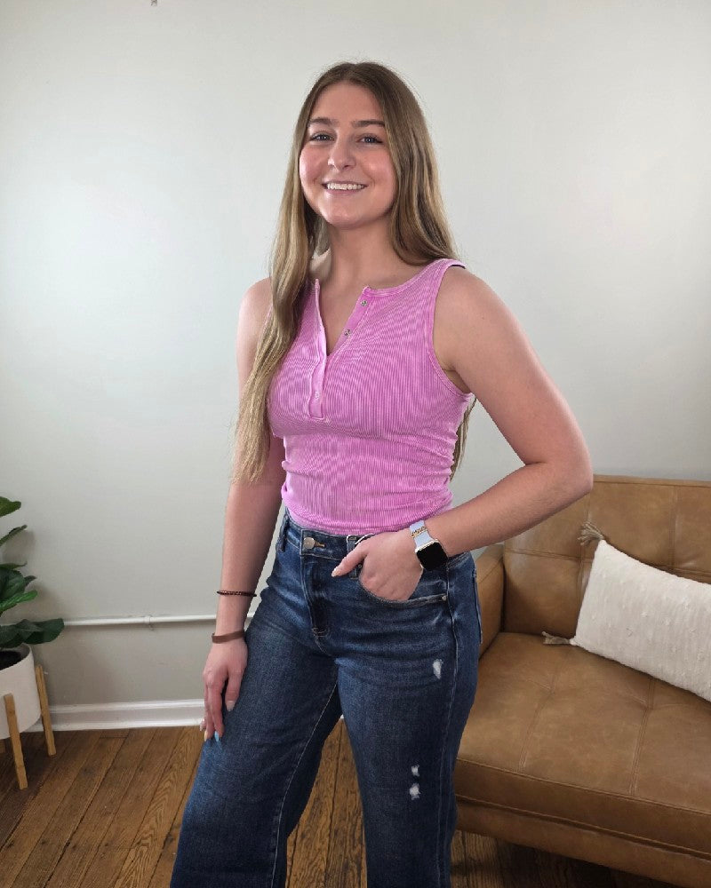 Woman wearing the Anja ribbed Henley tank in mauve standing in a living room. 