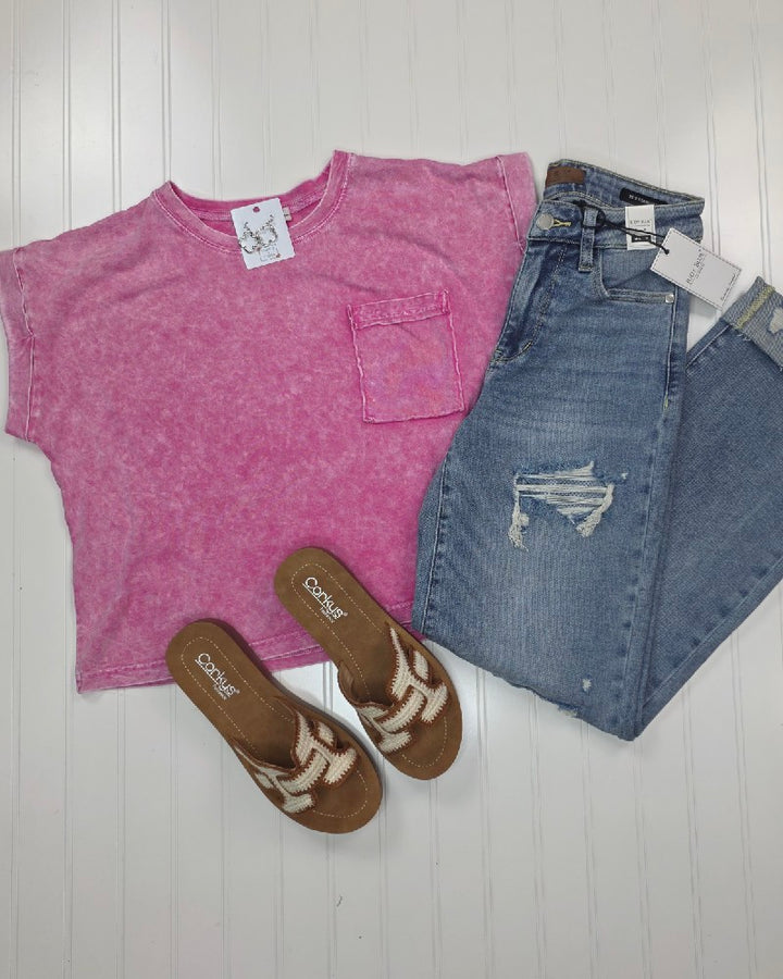 The ZENANA Candace Snow Washed Cropped Short Sleeve Top in pink, paired with light blue ripped jeans and tan slip-on sandals with white crisscross straps, creates an effortless casual summer look on a white surface.