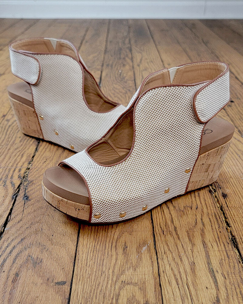 The Frisky Sandal from Corkys features beige mesh uppers, cork heels, and gold stud accents for a stylish look and comfort—shown here on a wooden floor.