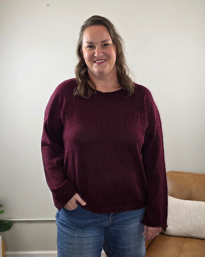A woman wearing a long-sleeved burgundy Ella Long Sleeve Sweater by blu pepper and blue jeans.