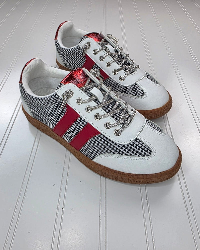 The Corkys Heads Up Black White Houndstooth Shoe features houndstooth fabric, white leather accents, red metallic stripes, silver eyelets, white laces, and light brown rubber soles, displayed on a grooved white surface.