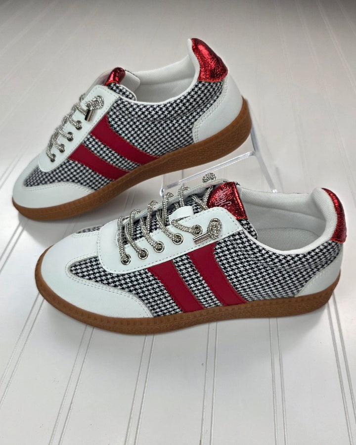 The Corkys Heads Up Black White Houndstooth Shoe features a stylish houndstooth pattern, red metallic heel accents, red side stripes, white uppers, and gum soles, shown on a white textured surface.