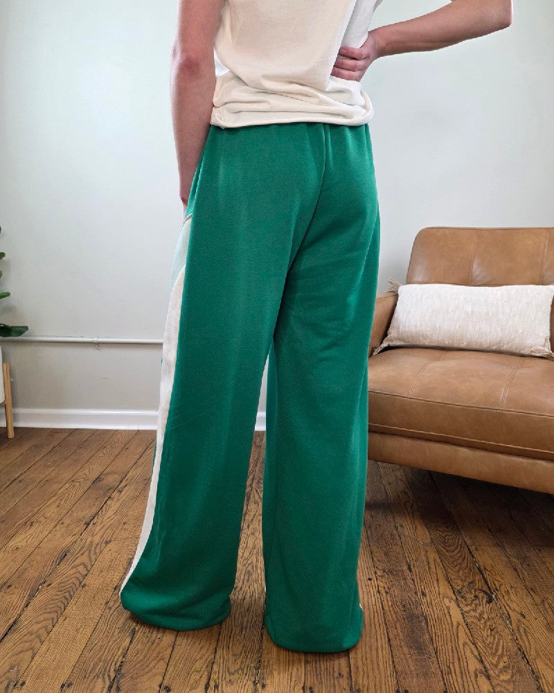 Person wearing the Trinity Wide Leg Lounge pants in green in a living room setting with a brown couch and white wall.