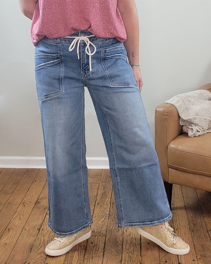 A person wearing Vervet's Reassure Wide Leg Jeans and a pink shirt.