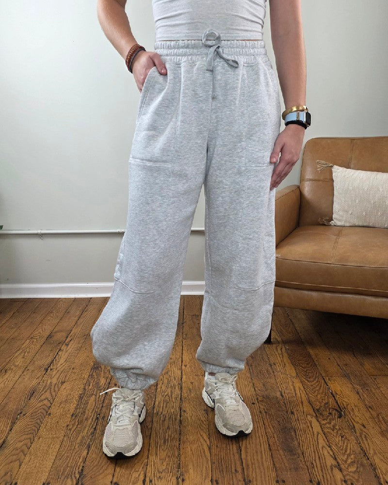 Amy Grey Joggers in heather grey with a drawstring waist and elastic cuffs, paired with athletic sneakers.