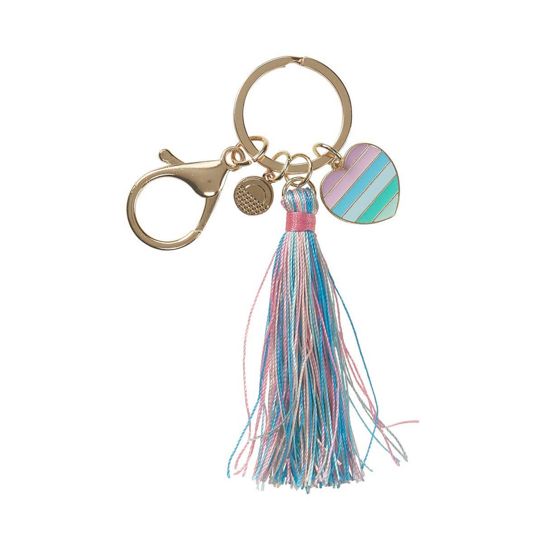 The OOLY Carrie Keychain features a gold lobster clasp, a pastel-striped enamel heart charm, and a long multicolored tassel in pink, blue, and white threads.