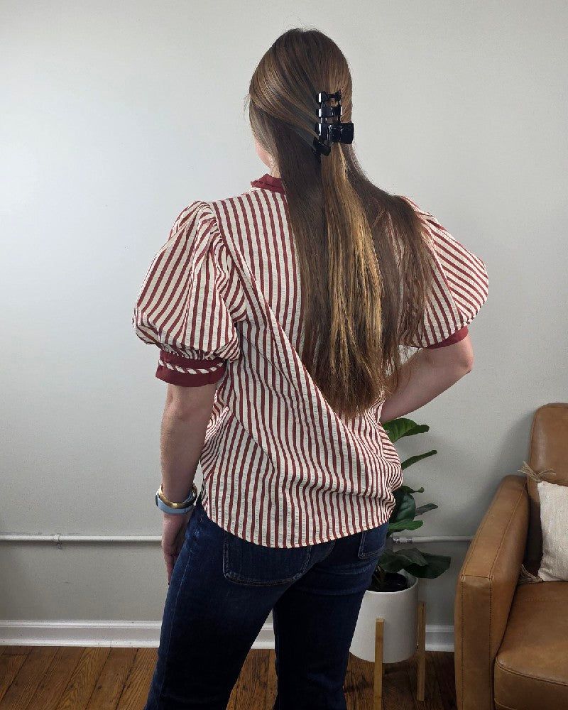 Back view of a person wearing a red and white vertical stripe Brittany V neck Puff Sleeve Stripe Blouse with red trim on the cuffs and collar.