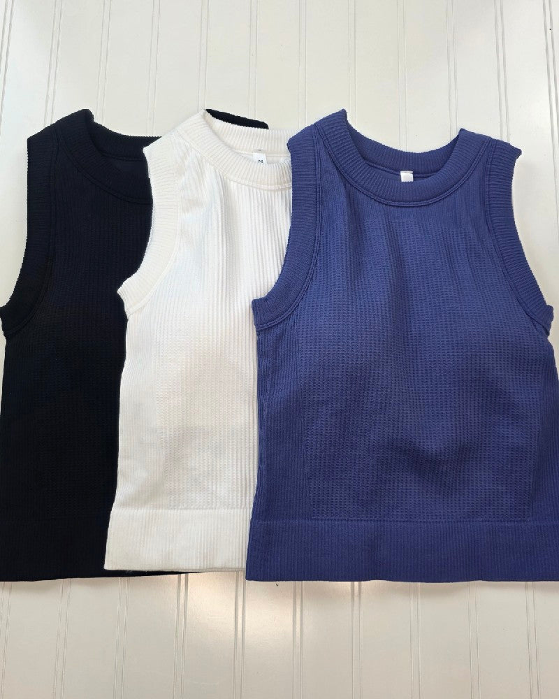 The Burke cropped tank top - laying flat in all three colors: black, white and marlin (blueish purple).