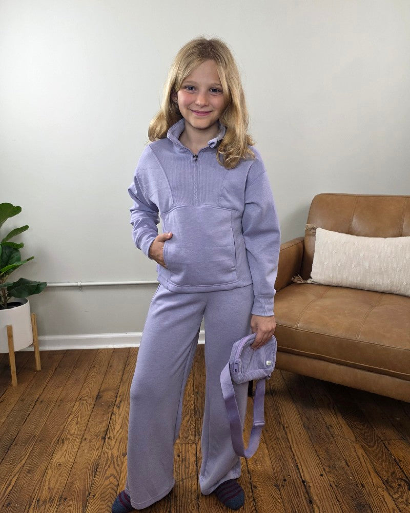 A girl wearing a lavender Davina Tween Girls Half Zip, Wide Leg Pants and Bag Set, consisting of a mock neck sweatshirt, matching wide-leg joggers, and a small crossbody bag.