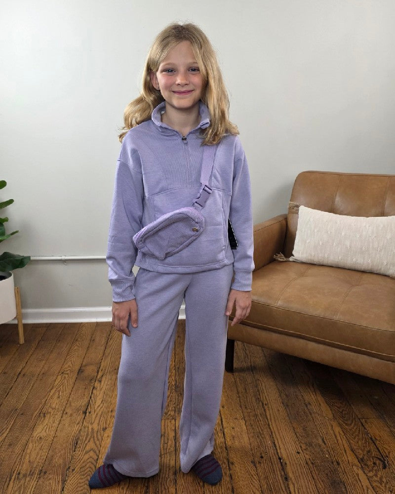 A girl wearing a lavender 90 Degree by Reflex Davina Tween Girls Half Zip, Wide Leg Pants and Bag Set, consisting of a mock neck sweatshirt, wide-leg joggers, and a crossbody belt bag.