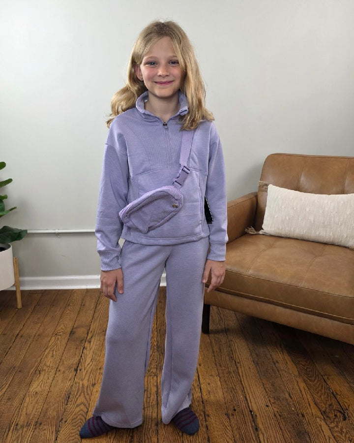 A girl wearing a lavender 90 Degree by Reflex Davina Tween Girls Half Zip, Wide Leg Pants and Bag Set, consisting of a mock neck sweatshirt, wide-leg joggers, and a crossbody belt bag.