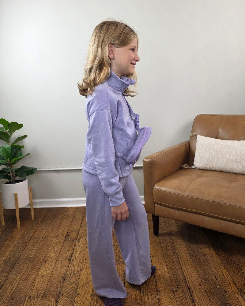 A girl wearing a lavender Davina Tween Girls Half Zip, Wide Leg Pants and Bag Set, featuring a matching mock neck sweatshirt, wide-leg joggers, and a small crossbody bag.