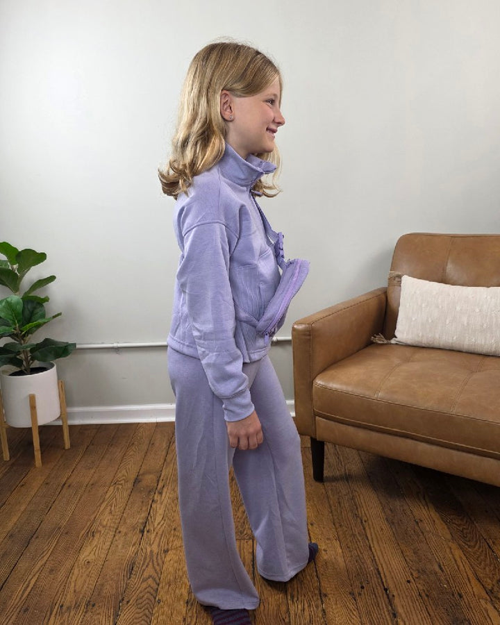 A girl wearing a lavender Davina Tween Girls Half Zip, Wide Leg Pants and Bag Set, featuring a matching mock neck sweatshirt, wide-leg joggers, and a small crossbody bag.