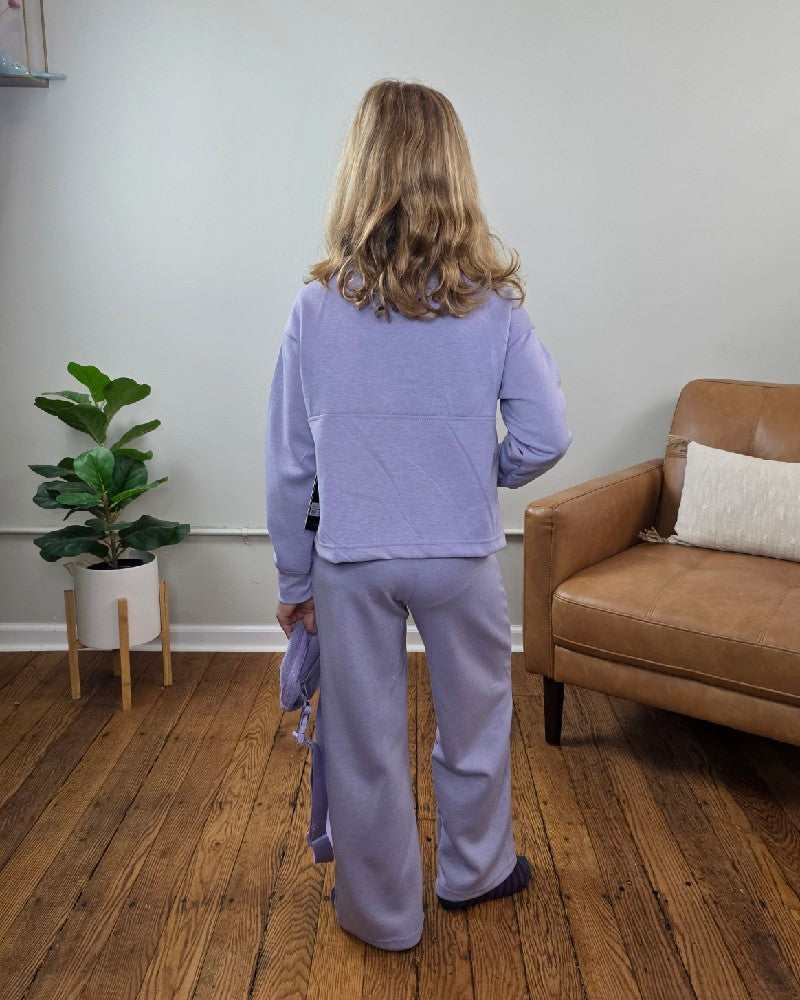 A girl seen from the back wearing the Davina Tween Girls Half Zip, Wide Leg Pants and Bag Set by 90 Degree by Reflex in lavender, holding the matching bag.