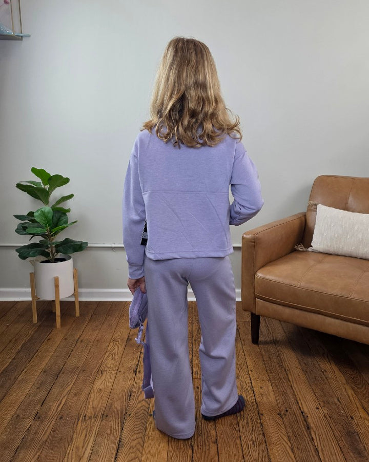 A girl seen from the back wearing the Davina Tween Girls Half Zip, Wide Leg Pants and Bag Set by 90 Degree by Reflex in lavender, holding the matching bag.