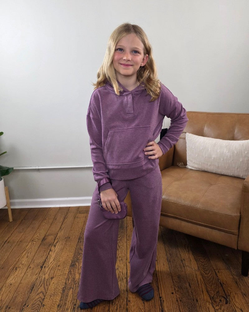 A girl wears a cozy 90 Degree by Reflex Ellen Tween Girls Snap Hoodie, Wide Leg Pants and Wristlet Set, holding a small wristlet.