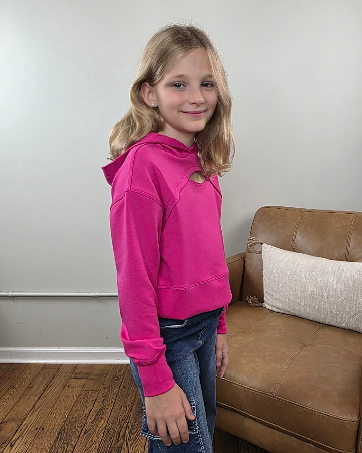 A girl wears a bright pink Erin Tween Girls Cutout Scuba Hoodie by 90 Degree by Reflex, featuring long sleeves and a cutout detail at the neckline.