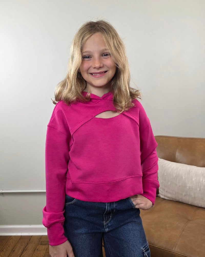 A girl smiles while wearing a bright pink 90 Degree by Reflex Erin Tween Girls Cutout Scuba Hoodie featuring a cutout detail at the neckline.