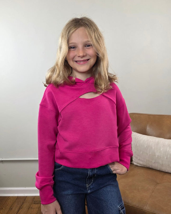 A girl smiles while wearing a bright pink 90 Degree by Reflex Erin Tween Girls Cutout Scuba Hoodie featuring a cutout detail at the neckline.