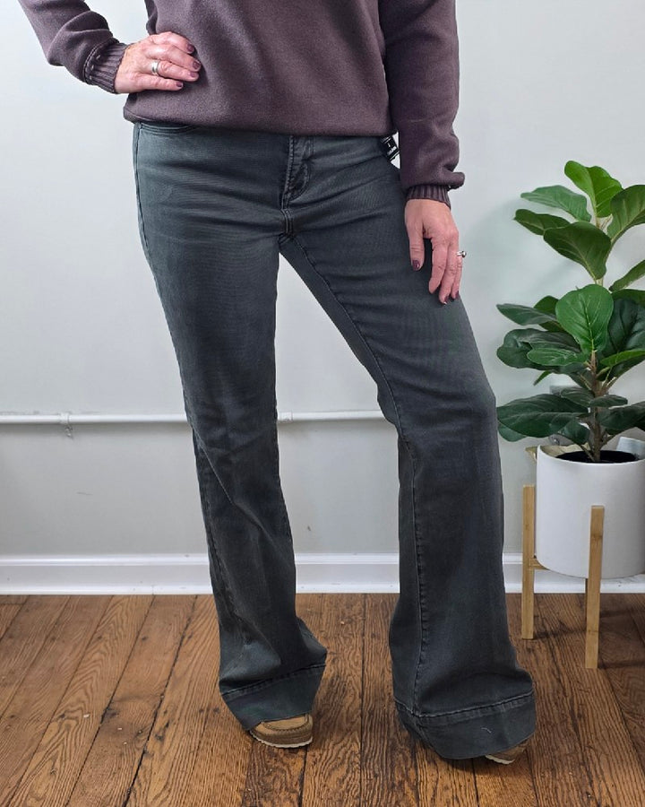 A person wearing Jessica High Rise, Olive Flares from Risen with Tummy Control and a brown sweater.