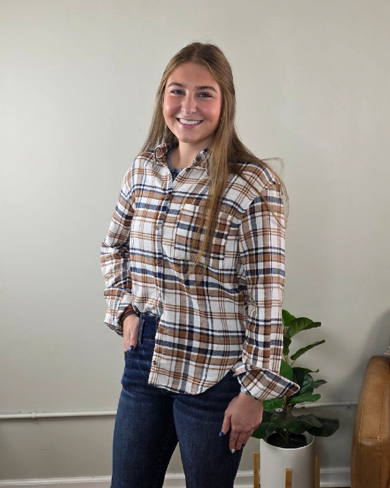 A smiling woman wears a cream-colored brown plaid Kimberly Plaid Flannel Long Sleeve by Love Tree tucked into dark blue jeans.