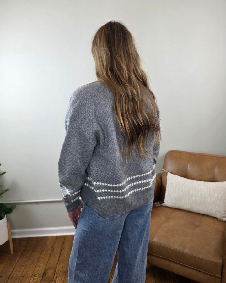 A person seen from behind wears a grey Sierra Honeycomb Textured Cardigan with two white horizontal stripes near the hem, paired with blue jeans.