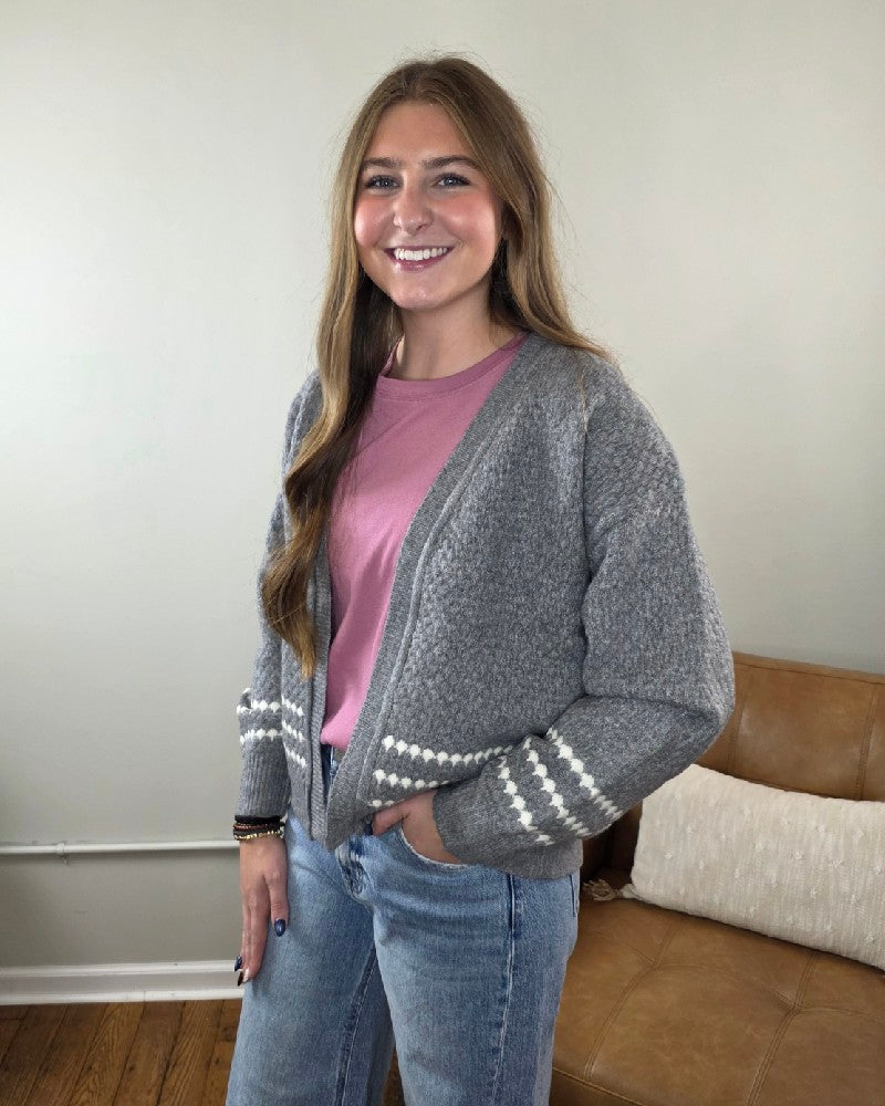 A person wearing a grey Sierra Honeycomb Textured Cardigan over a pink shirt and blue jeans.