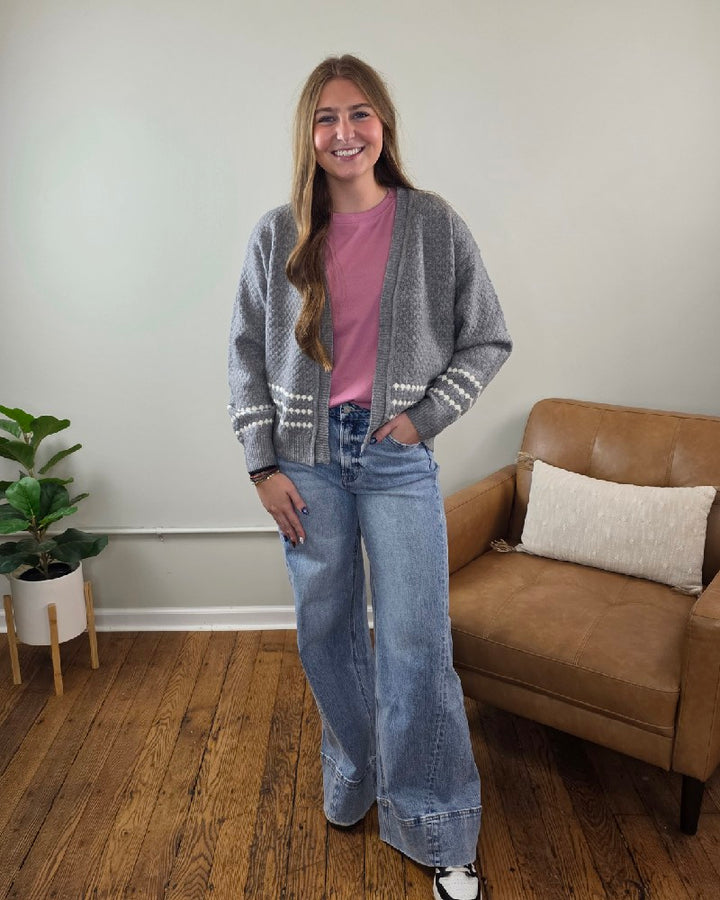 A woman wearing a Staccato Sierra Honeycomb Textured Cardigan with white horizontal stripes over a pink t-shirt and wide-leg jeans.