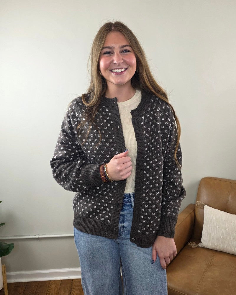 A person wearing a chocolate brown Staccato Sylvia Detailed Button Down Sweater with a white floral pattern over a cream-colored top and light-wash jeans.