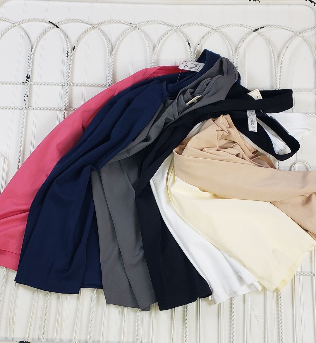 A selection of Yelete Group Wide Strap Layering Tanks in various colors is displayed on a white, textured wavy surface.