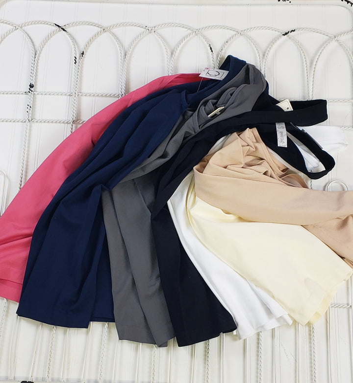 A selection of Yelete Group Wide Strap Layering Tanks in various colors is displayed on a white, textured wavy surface.