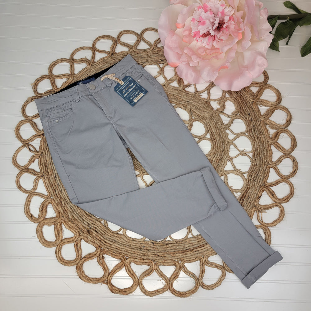 “Ab Solution” Ankle Skimmers in Dove Gray by Democracy are neatly folded on a woven mat with a pink flower, set against a white wooden backdrop for a clean, stylish display.
