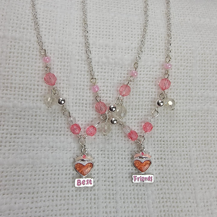Two necklaces from 2HOPE Accessories, Inc's Girls Charm Jewelry: Best Friends Sets feature pink and clear beads and heart-shaped pendants reading "Best" and "Friends," making perfect friendship jewelry with charming pink heart details.