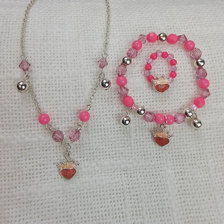 Girls Charm Jewelry: 3 pc Sets by 2HOPE Accessories, Inc includes an adjustable necklace, bracelet, and ring with pink and silver beads plus heart and crown charms, displayed on a white textured fabric background.
